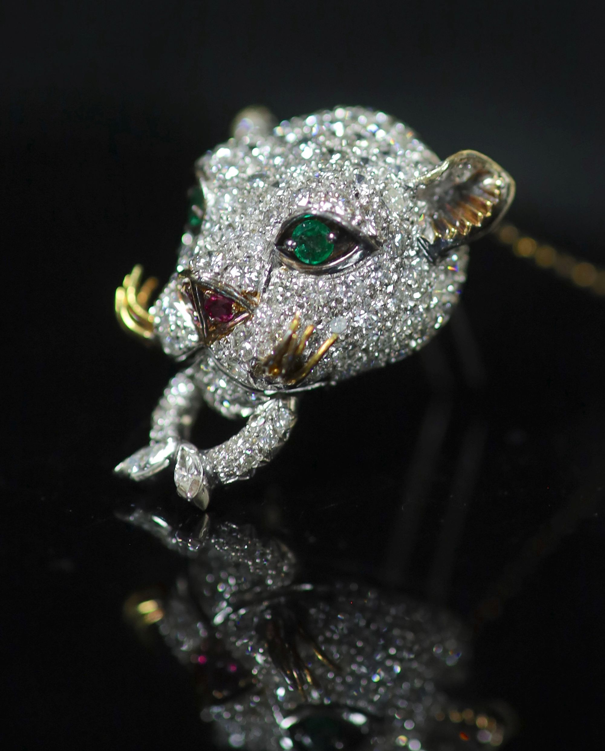 An 18K white gold and diamond leopard's head clip brooch, with emerald eyes, ruby nose and gold whiskers,